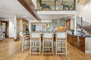 Kitchen with beamed ceiling, a breakfast bar, a kitchen island, light wood-type flooring, and recessed lighting