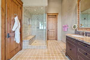 Full bathroom with a tile shower, vanity, and tile patterned floors