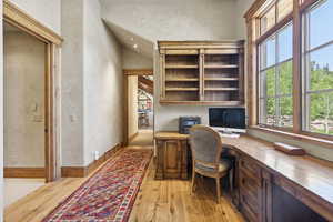 Home office with built in desk and light wood-style flooring