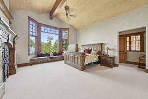 Carpeted bedroom with a wood ceiling with exposed beams, high vaulted ceiling, a fireplace, and ceiling fan
