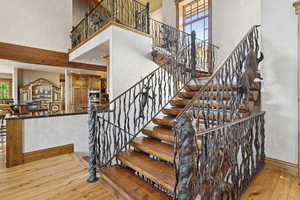 Staircase featuring wood-type flooring and a towering ceiling