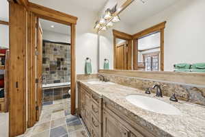 Bathroom with double vanity, recessed lighting, stone finish flooring, and tiled shower / bath