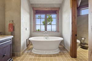 Full bath featuring plenty of natural light, a soaking tub, and vanity