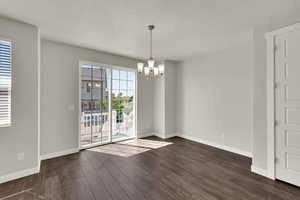 Unfurnished dining area featuring a chandelier, dark wood-type flooring, and a textured ceiling