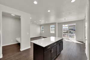 Kitchen featuring a textured ceiling, recessed lighting, healthy amount of natural light, dark wood-type flooring, and light countertops