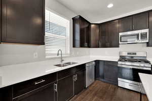Kitchen featuring appliances with stainless steel finishes, dark wood finished floors, light countertops, dark brown cabinetry, and recessed lighting