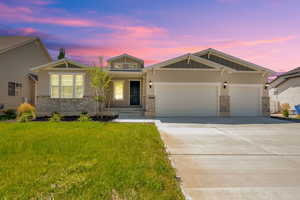 View of front facade with stone siding, a garage, concrete driveway, a front yard, and board and batten siding
