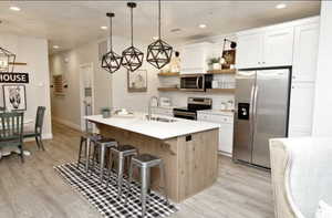 Kitchen featuring open shelves, appliances with stainless steel finishes, recessed lighting, light countertops, and light wood-style flooring