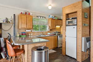 Kitchen featuring a peninsula, white appliances, heating unit, a kitchen breakfast bar, and dark wood-style flooring