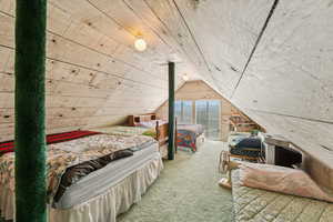 Bedroom featuring carpet, lofted ceiling, and wood walls