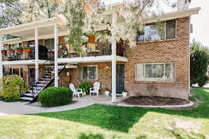 Rear view of house with brick siding, a lawn, and stairway