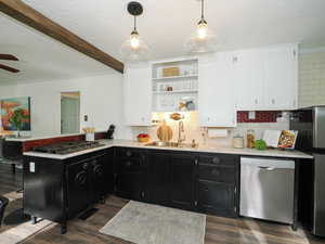 Kitchen featuring dark cabinetry, crown molding, white cabinetry, appliances with stainless steel finishes, and tasteful backsplash