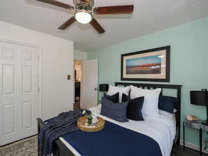 Bedroom featuring a textured ceiling, wood finished floors, and a ceiling fan