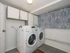 Washroom with cabinet space, washer and dryer, and tile patterned floors