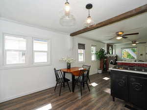 Dining area featuring healthy amount of natural light, dark wood-style floors, beam ceiling, a fireplace, and ceiling fan