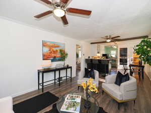 Living area featuring ceiling fan, a textured ceiling, wood finished floors, and crown molding