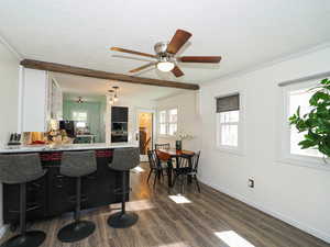 Kitchen with dark wood finished floors, stainless steel appliances, a textured ceiling, a kitchen bar, and ceiling fan