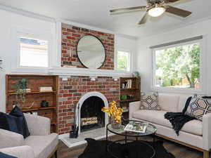 Living area with ornamental molding, wood finished floors, a brick fireplace, and a ceiling fan