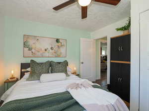 Bedroom with a textured ceiling, wood finished floors, and ceiling fan