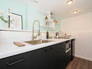 Kitchen featuring dark cabinetry, light countertops, dark wood-style flooring, and open shelves
