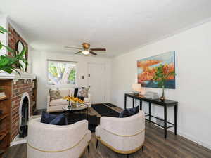 Living area with ceiling fan, wood finished floors, a textured ceiling, ornamental molding, and a brick fireplace