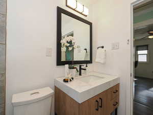Half bath with vanity, wood finished floors, and ceiling fan