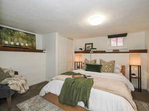 Bedroom with carpet floors, a textured ceiling, and a closet