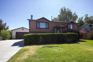 Split level home with concrete driveway, massive, detached 2-car garage.