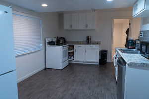 Kitchen with white appliances, light countertops, white cabinets, dark wood-type flooring, and recessed lighting