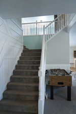 Stairs featuring a textured ceiling and a towering ceiling