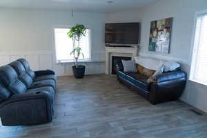 Living area featuring wainscoting, a glass covered fireplace, wood finished floors, and a decorative wall
