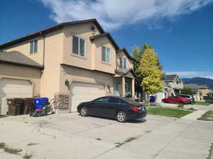 Traditional home featuring concrete driveway, stucco siding, and an attached garage