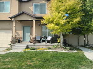 View of front facade with covered porch, stucco siding, and a front lawn