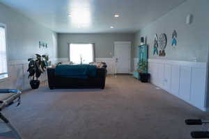 Carpeted living room with wainscoting, a decorative wall, and recessed lighting
