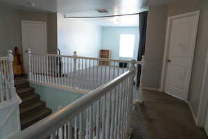 Hallway with an upstairs landing and dark carpet