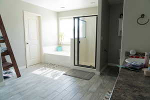 Full bathroom with a garden tub, light wood-style floors, and a stall shower