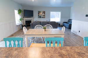 Dining room featuring wainscoting, a decorative wall, wood finished floors, and a fireplace