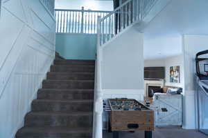 Staircase featuring a wainscoted wall, a fireplace, a towering ceiling, and a decorative wall