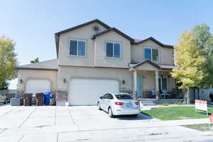 Traditional-style house with stone siding, covered porch, stucco siding, and driveway