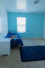 Carpeted bedroom featuring a textured ceiling and baseboards