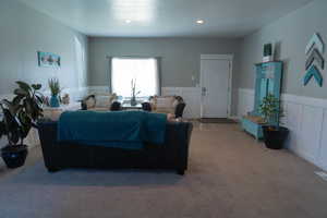 Living room featuring a wainscoted wall, a decorative wall, carpet flooring, and recessed lighting