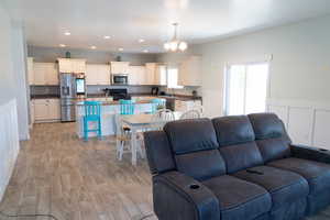 Living area featuring a chandelier, light wood-style floors, recessed lighting, a wainscoted wall, and a decorative wall