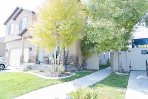 View of front of home with stone siding, stucco siding, a gate, and covered porch