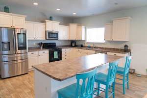 Kitchen featuring a kitchen bar, appliances with stainless steel finishes, a center island, recessed lighting, and light wood finished floors