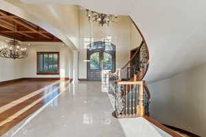 Entryway featuring arched walkways, a chandelier, coffered ceiling, decorative columns, and crown molding