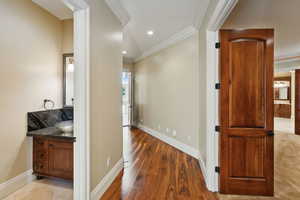 Hall with wood finished floors, ornamental molding, and recessed lighting