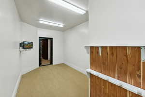 Empty room with light colored carpet and baseboards