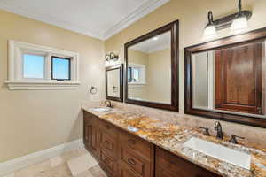 Full bath featuring double vanity, ornamental molding, and decorative backsplash