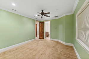 Unfurnished room with light carpet, a ceiling fan, and crown molding