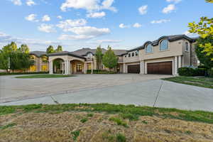 French country style house featuring concrete driveway, stucco siding, an attached garage, and stone siding